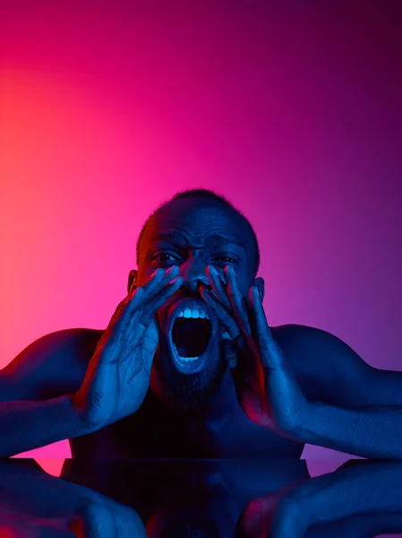 Close up portrait of a young naked african man screaming at camera indoors