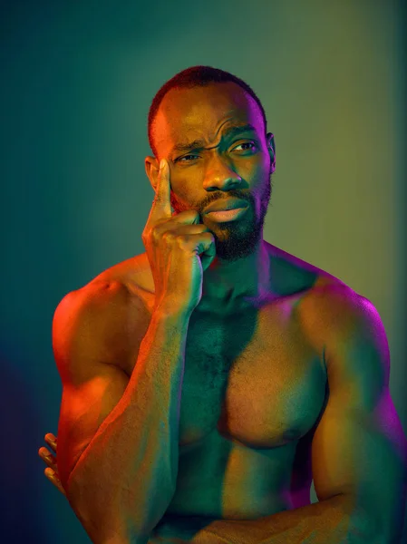 Close up portrait of a young naked african man looking at camera indoors