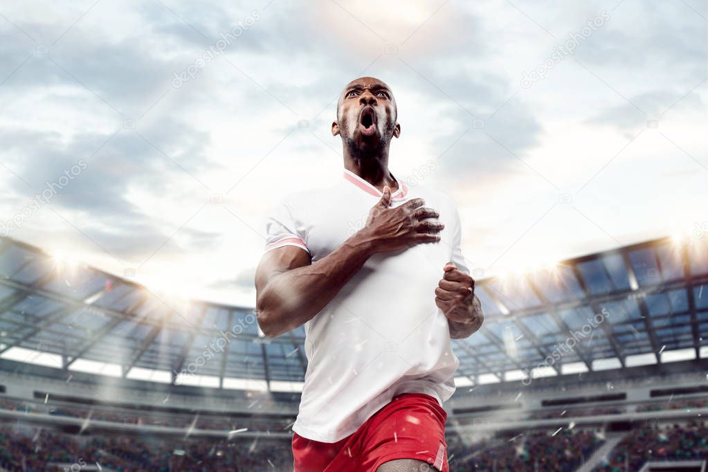 The football player in motion on the field of stadium