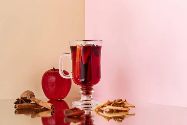 Mulled wine in glass with cinnamon stick, christmas sweets on on the glass table