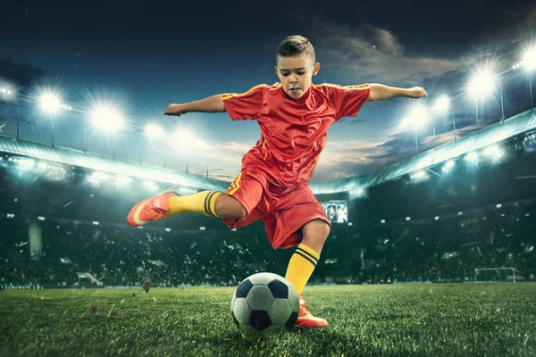 Niño con pelota de fútbol haciendo patada voladora en el estadio —  Fotos de Stock