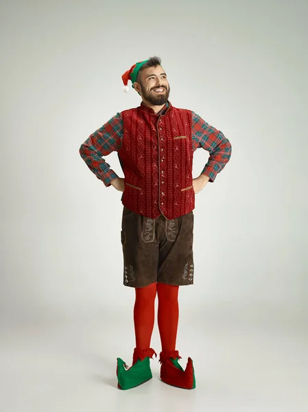 Hombre amigable vestido como un gnomo divertido posando sobre un fondo gris aislado — Foto de Stock