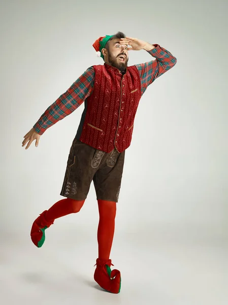 Hombre amigable vestido como un gnomo divertido posando sobre un fondo gris aislado — Foto de Stock