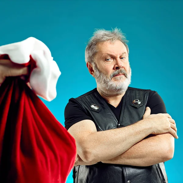 Ein älterer Mann mit weißem Haar und Bart und Weihnachtsgeschenktüte. — Stockfoto