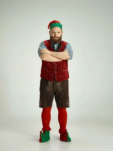 Hombre amigable vestido como un gnomo divertido posando sobre un fondo gris aislado — Foto de Stock