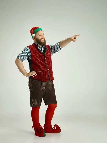 Hombre amigable vestido como un gnomo divertido posando sobre un fondo gris aislado — Foto de Stock