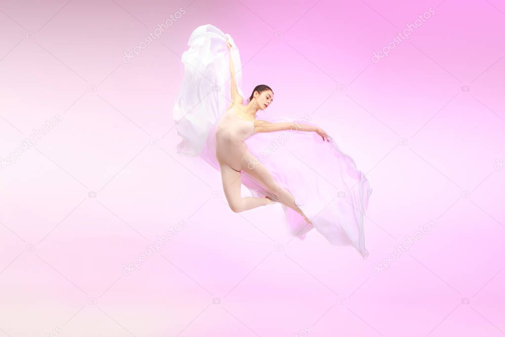 Ballerina. Young graceful female ballet dancer dancing over pink studio. Beauty of classic ballet.