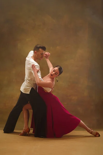 Tanzpaar in goldenem Kleid tanzt auf Studiohintergrund. — Stockfoto