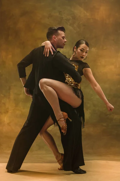 Dance ballroom couple in gold dress dancing on studio background.