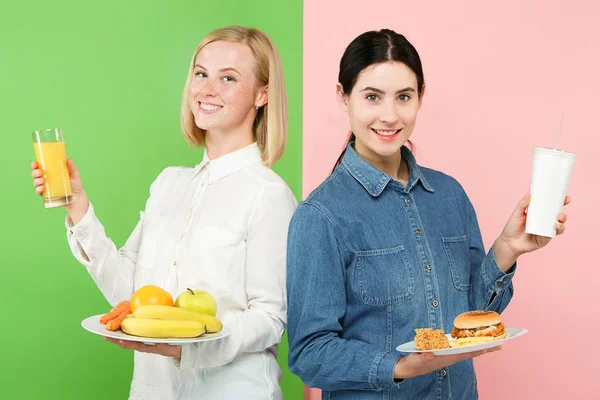 Diet. Dieting concept. Healthy Food. Beautiful Young Women choosing between fruits and unhelathy fast food — Stock Photo, Image