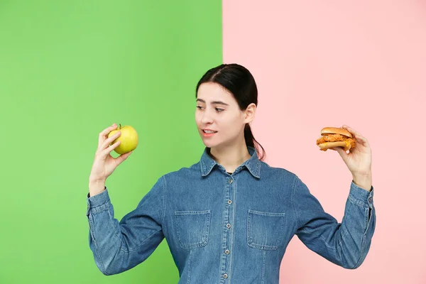 Ernährung. Diätkonzept. Gesunde Ernährung. schöne junge Frau, die zwischen Früchten und unhelathy Fast Food wählen kann — Stockfoto