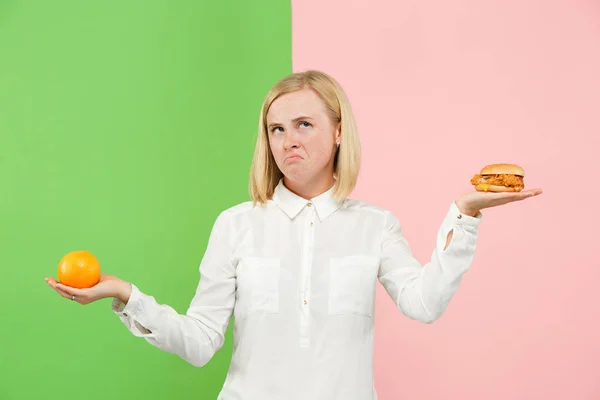 Dieta. Il concetto di dieta. Cibo sano. Bella giovane donna che sceglie tra frutta e fast food unhelathy — Foto Stock