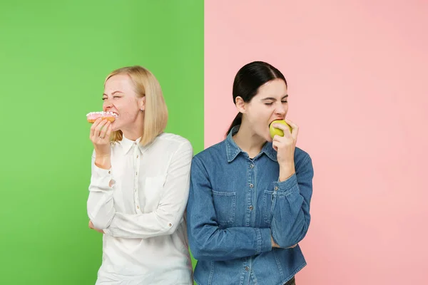 Ernährung. Diätkonzept. Gesunde Ernährung. schöne junge Frauen, die zwischen Früchten und unhelathy Kuchen wählen — Stockfoto