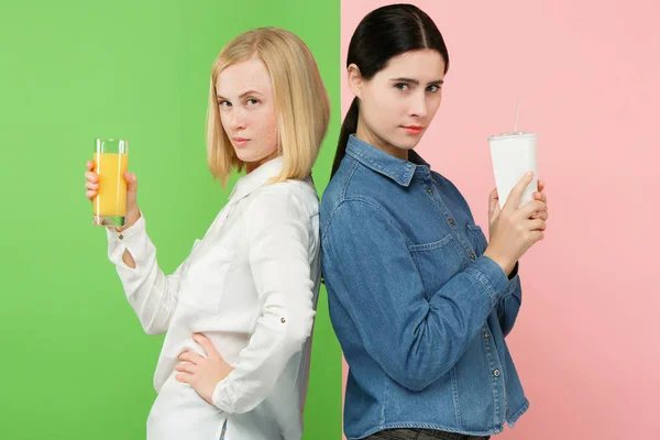 Régime alimentaire. Concept de régime. Nourriture saine. Belles jeunes femmes au choix entre jus d'orange de fruits et boisson sucrée gazeuse sans héliathie — Photo