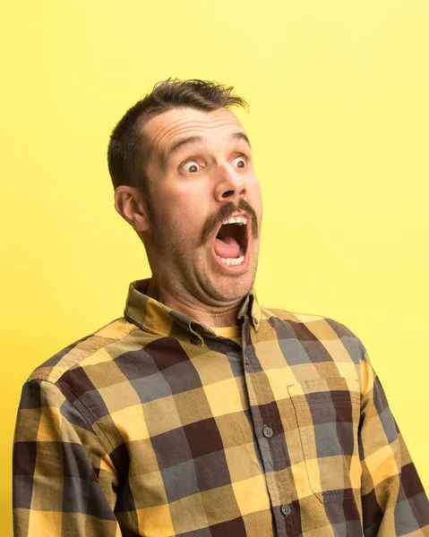 Mies huutaa avoimella suulla eristetty keltaisella pohjalla, käsite kasvot tunteita — kuvapankkivalokuva