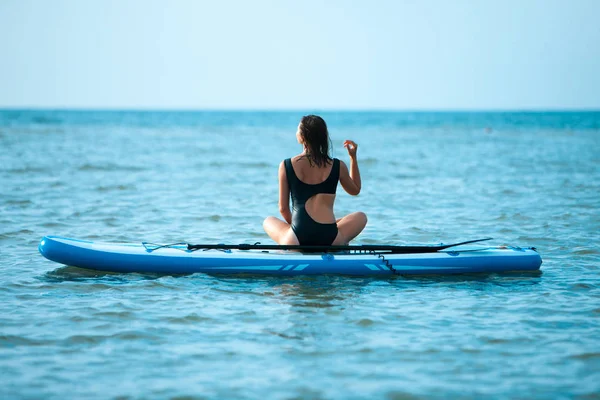 Счастливая красивая молодая девушка с доской на пляже. Синее море на заднем плане. Летние каникулы . — стоковое фото