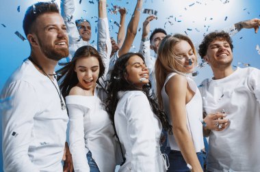 Gençlerin grup ayakta ve birlikte kutluyor mavi arka plan üzerinde neşeli neşeli
