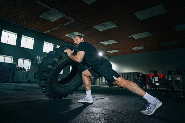 Shirtless man flipping zware band op sportschool — Stockfoto