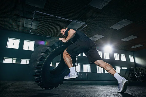 Без сорочки чоловік підкидає важкі шини в спортзалі — стокове фото