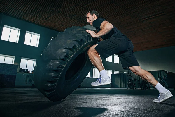 Shirtless man flipping zware band op sportschool — Stockfoto