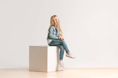 Kameraya bakarak ve gülümseyen şık kot elbise sevimli küçük çocuk portresi