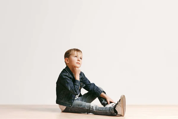 O retrato de menino bonito em roupas de jeans elegantes olhando para a câmera no estúdio — Fotografia de Stock