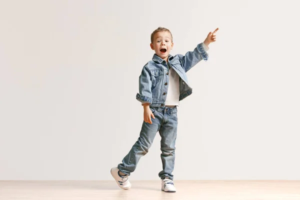 Porträttet av söt liten pojke i snygga jeans kläder tittar kameran på studio — Stockfoto