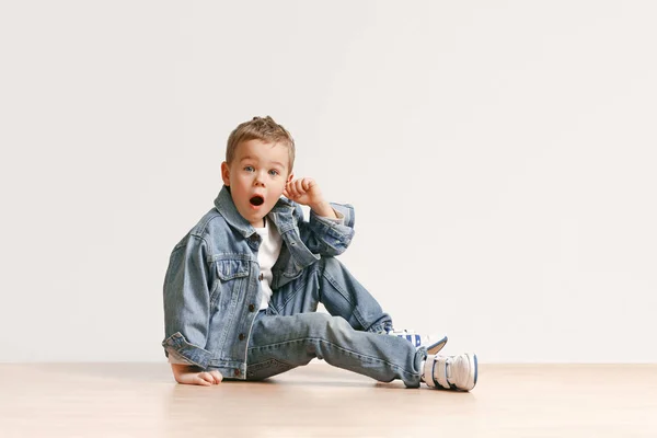 Das Porträt des süßen kleinen Jungen in stylischer Jeans-Kleidung, der im Studio in die Kamera schaut — Stockfoto