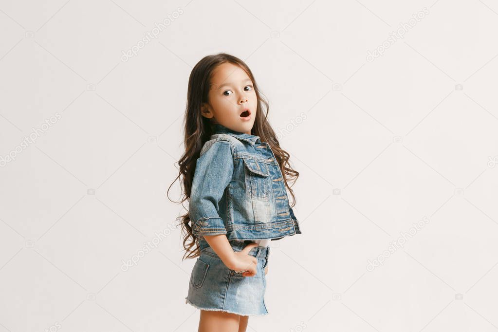 The portrait of cute little kid in stylish jeans clothes looking at camera and smiling