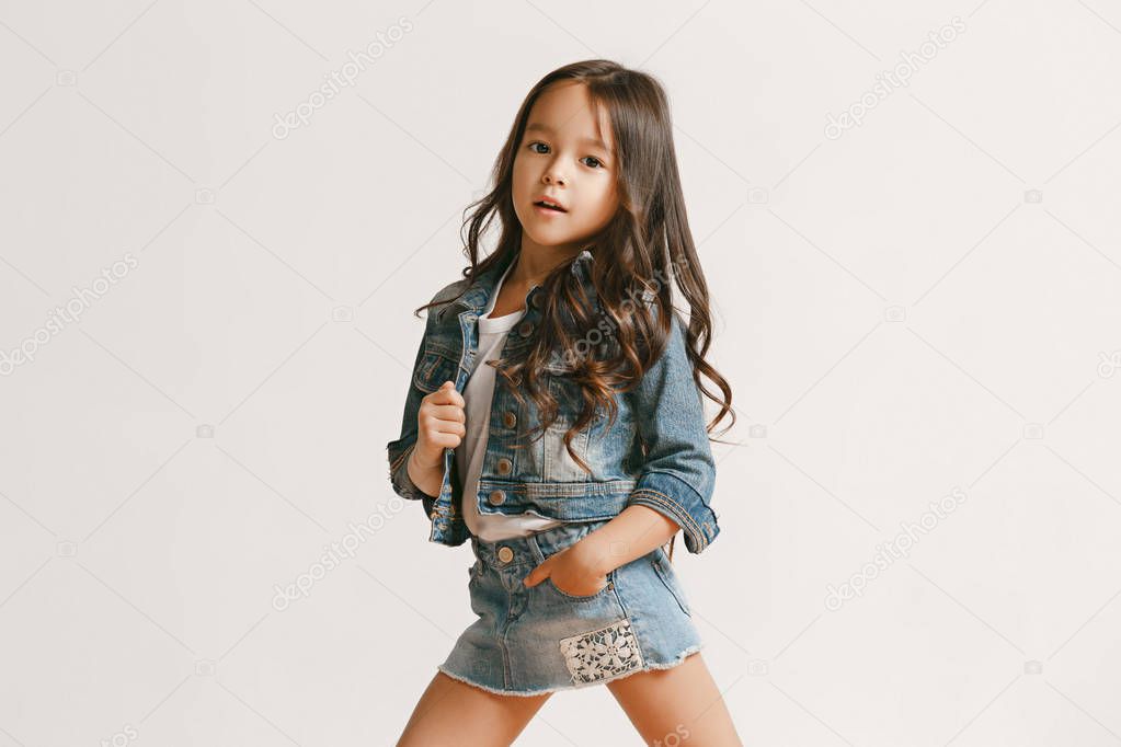 Full length portrait of cute little kid in stylish jeans clothes looking at camera and smiling