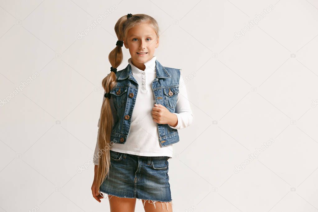 portrait of cute little teen in stylish jeans clothes looking at camera and smiling