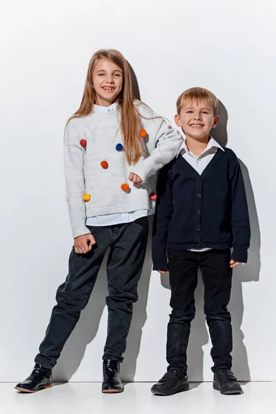 O retrato de menino e menina bonito em roupas de jeans elegantes olhando para a câmera no estúdio — Fotografia de Stock