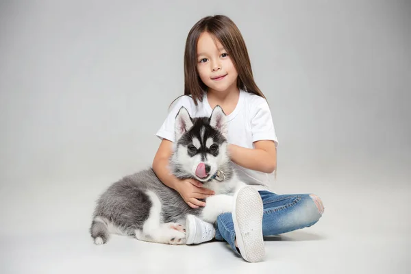 Portrait d'une petite fille joyeuse s'amusant avec chiot husky sibérien sur le sol au studio — Photo