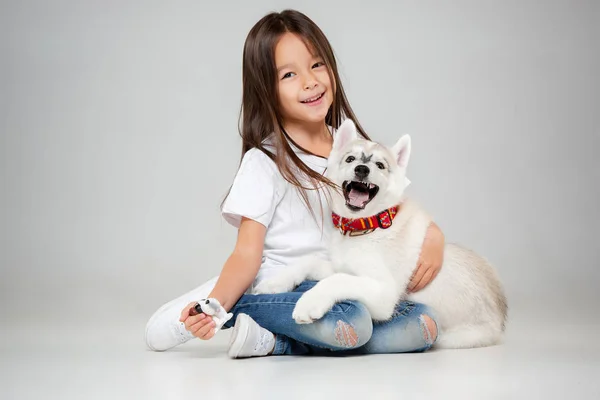 Portrait d'une petite fille joyeuse s'amusant avec chiot husky sibérien sur le sol au studio — Photo