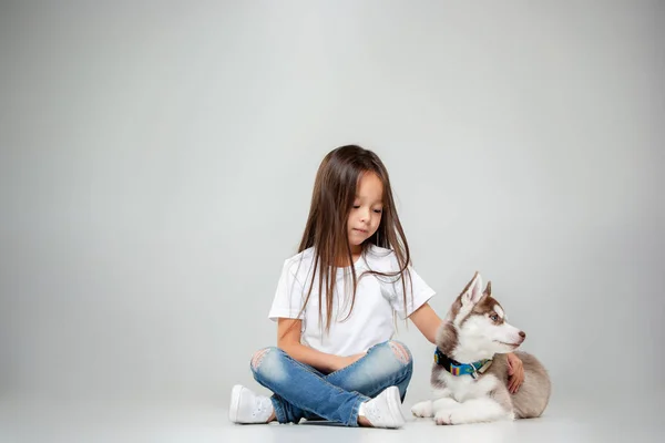 Portrait d'une petite fille joyeuse s'amusant avec chiot husky sibérien sur le sol au studio — Photo