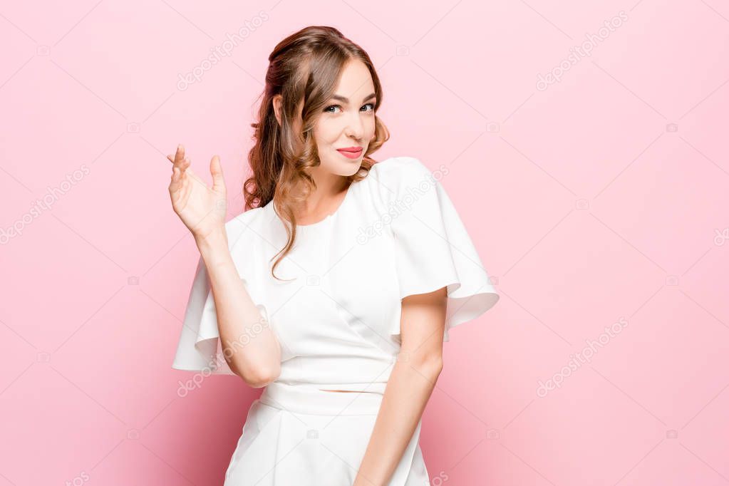 The happy business woman standing and smiling against pink background.