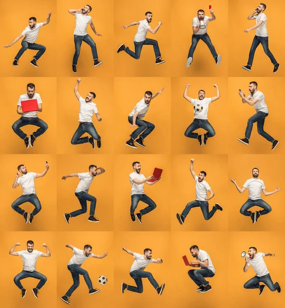 年轻男子在橙色背景下使用膝上型电脑跳跃时的图像. — 图库照片