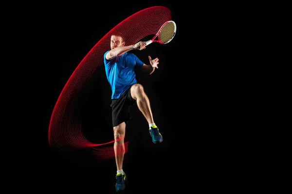 Um homem caucasiano jogando tenista em fundo preto — Fotografia de Stock