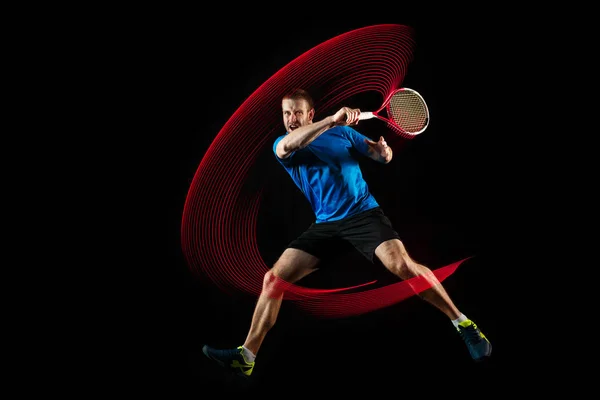 Um homem caucasiano jogando tenista em fundo preto — Fotografia de Stock
