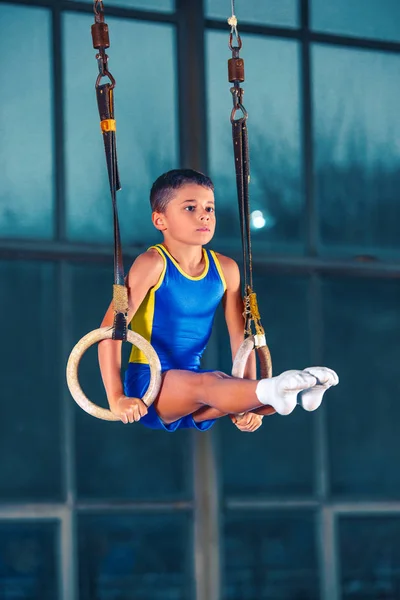 Volledige lengte rearview schot van een mannelijke atleet pull-ups uitvoeren op gymnastiek ringen. — Stockfoto