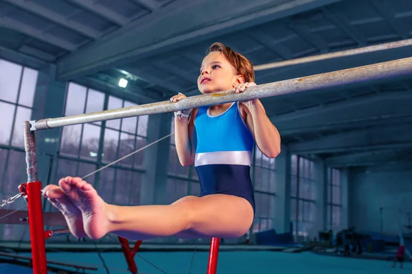 Bela menina está envolvida na ginástica esportiva em barras paralelas — Fotografia de Stock