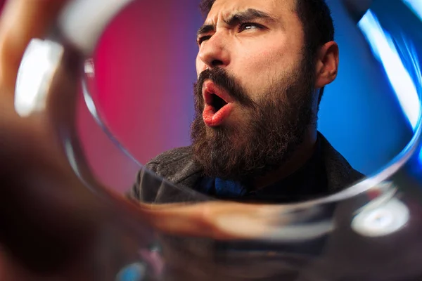 O jovem surpreso em roupas de festa posando com copo de vinho . — Fotografia de Stock