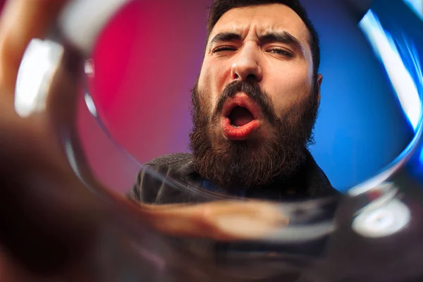 O jovem surpreso em roupas de festa posando com copo de vinho . — Fotografia de Stock