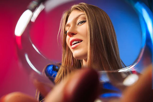 Překvapen, mladá žena v slavnostní oděv pózuje s sklenku vína. — Stock fotografie