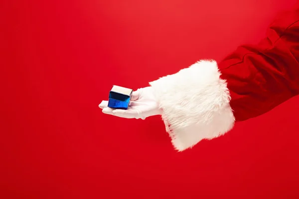 Hand van de Kerstman, bedrijf van een gift op rode achtergrond — Stockfoto