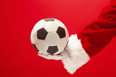 Noel Baba kırmızı zemin üzerine izole bir futbol topu tutan