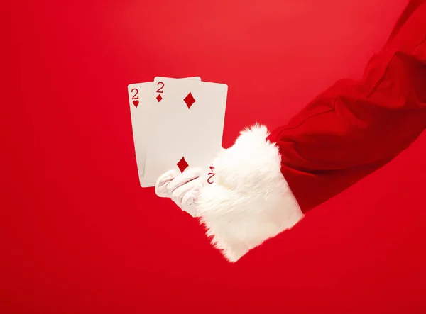 빨간색 배경에 재생 카드를 들고 하는 산타 클로스의 손 — 스톡 사진