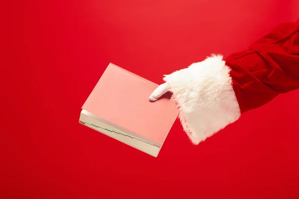 Hand van de Kerstman, houden een notitieboekje op rode achtergrond — Stockfoto