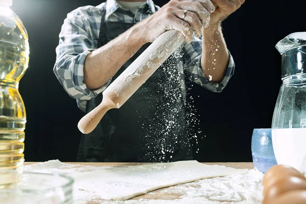Профессиональный мужчина повар посыпать тесто с мукой, preapares или печет хлеб за кухонным столом — стоковое фото