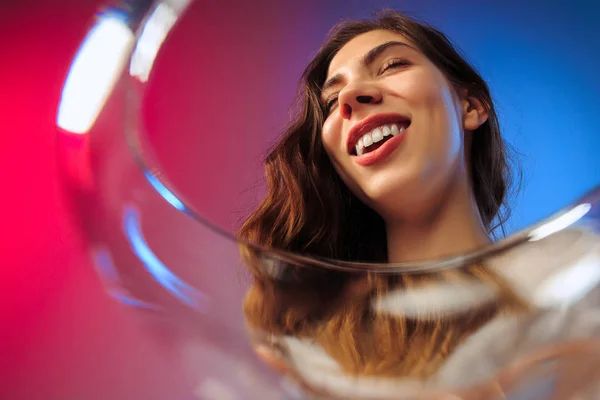 Удивлённая молодая женщина в праздничной одежде позирует с бокалом вина . — стоковое фото